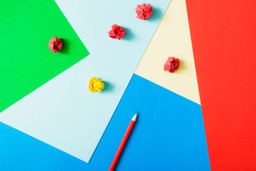 Zdjęcie przedstawiające kolorowe kartki i ołówek, czyli przedmioty, które mogą się przydać podczas tworzenia strategii komunikacji.