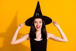 Młoda, roześmiana kobieta w czarnym kapeluszu czarodzieja.