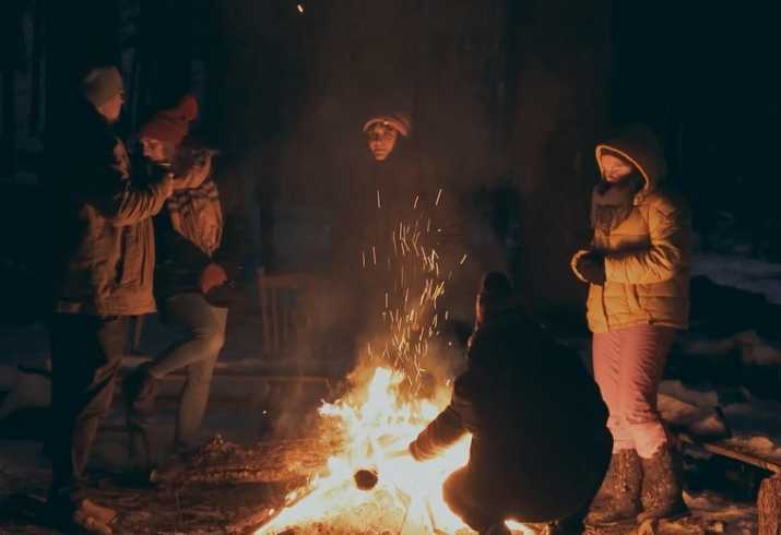 Ludzie zgromadzeni przy ognisku podczas spotkania inwestorów na terenie budowy Narusy Leśnej Przystani. Jest to kadr z filmu promocyjnego.